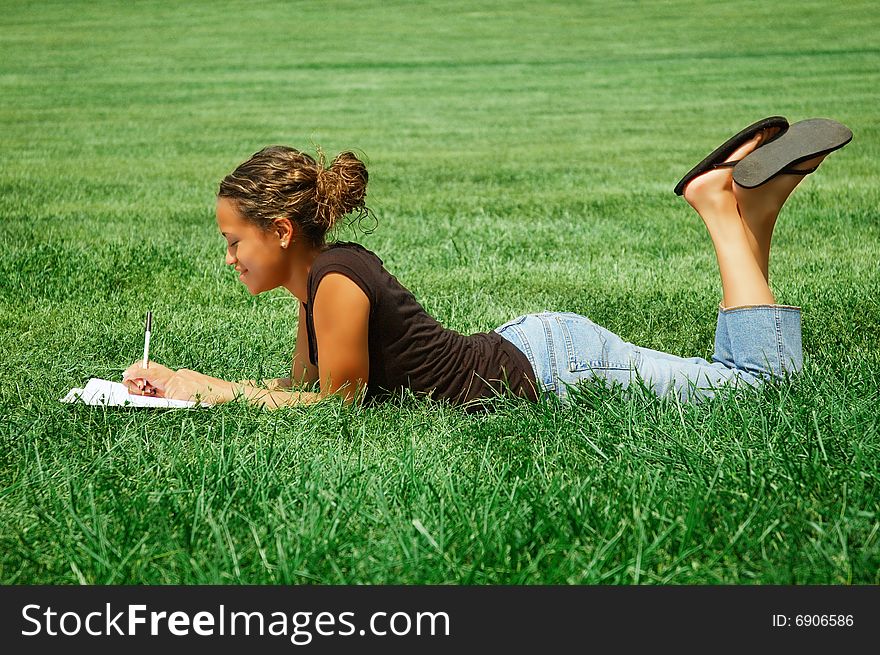 Beautiful young woman in green field with notebook. Beautiful young woman in green field with notebook.