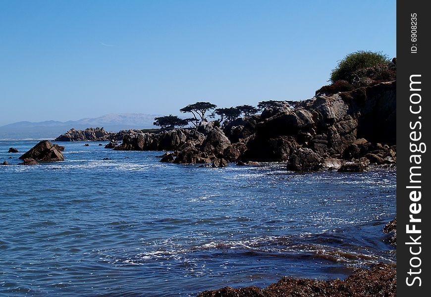 Rocky coast beneath a clear blue sky south of Santa Barbara, California.