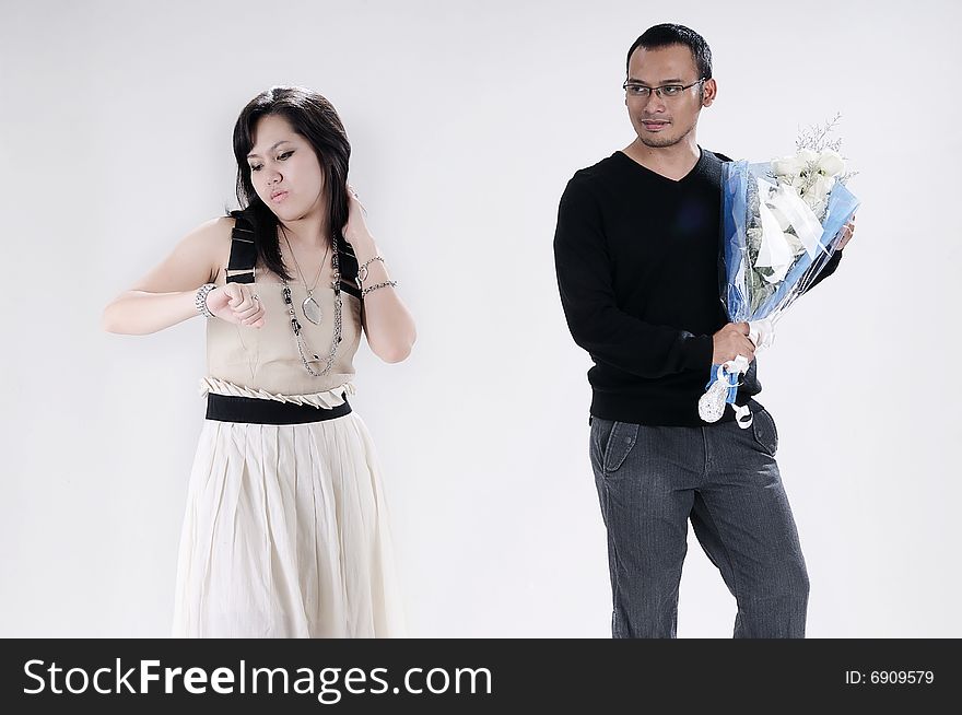 Man giving flowers and woman waiting looking at watch. Man giving flowers and woman waiting looking at watch