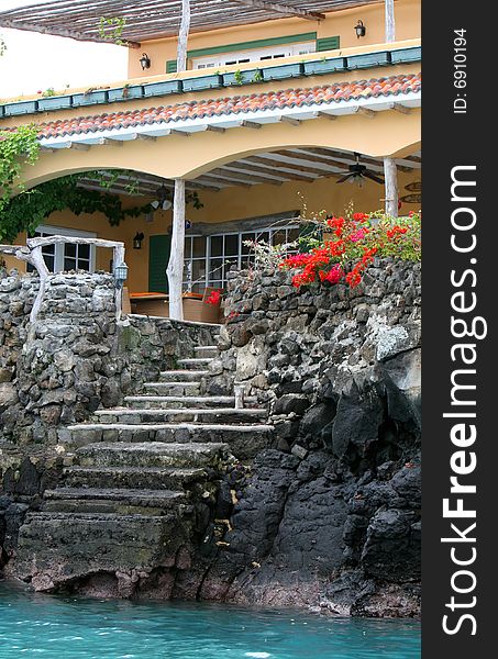 A colorful house behind stone steps which lead into blue waters. A colorful house behind stone steps which lead into blue waters