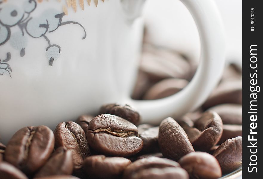 Close-up of coffee beans fith a cup in the background