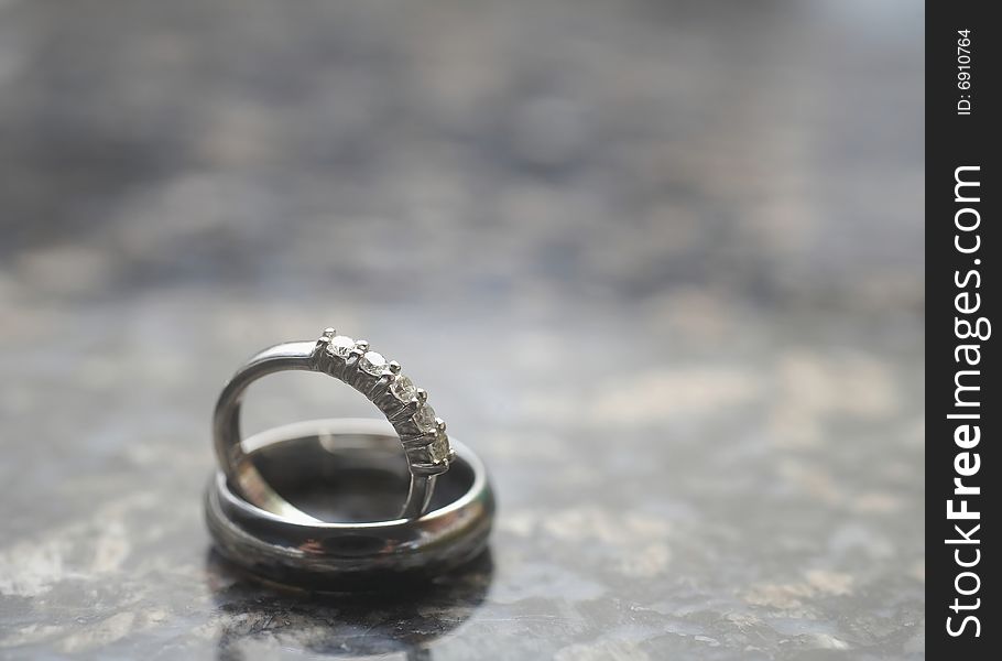 Closeup of silver wedding rings on marble DOF focus on diamonds