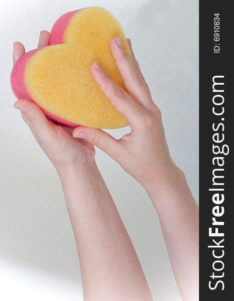Heart sponge in hands in the bath