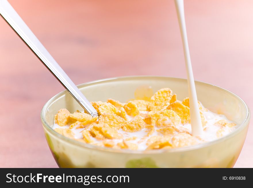 Corn flakes with milk and spoon on the table