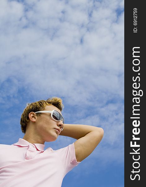 Portrait of a young man in sunglasses over blue sky
