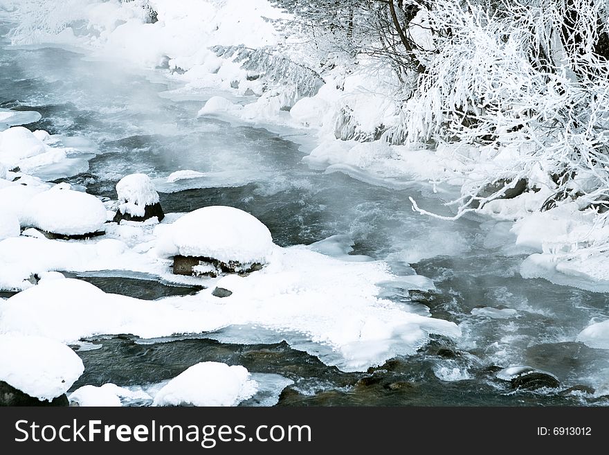 The small river in wood. From the river steam which hoarfrost settles on branches of trees and coastal stones rises. The small river in wood. From the river steam which hoarfrost settles on branches of trees and coastal stones rises.