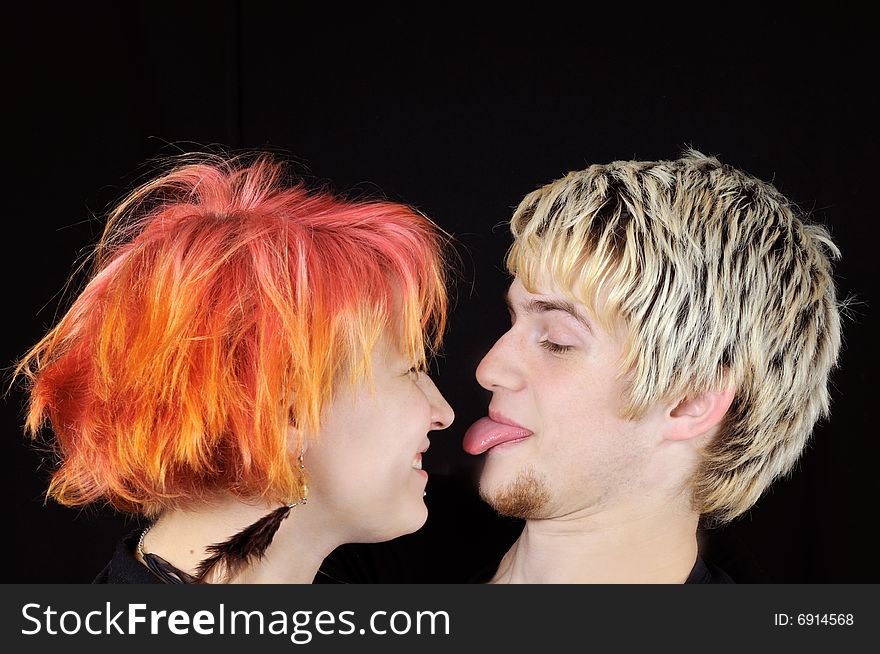 Handsome guy shows tongue to a pretty girl, on black background