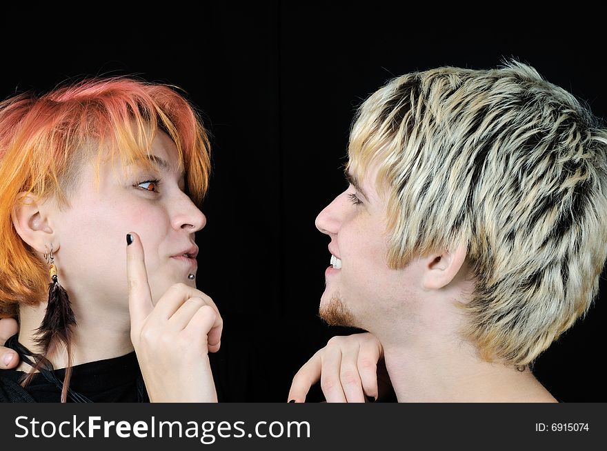 Young informal red-eyed girl wants to touch guy's nose, on black background. Young informal red-eyed girl wants to touch guy's nose, on black background