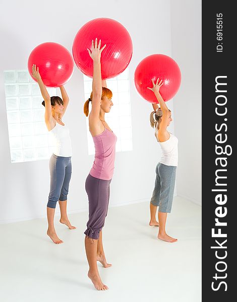 Group of women doing fitness exercise with big ball. They're looking at camera. Side view. Group of women doing fitness exercise with big ball. They're looking at camera. Side view.