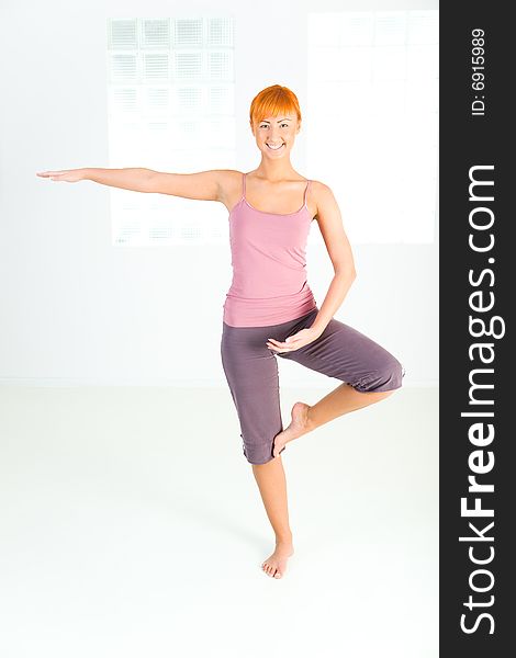 Young red-haired woman doing fitness exercise. She's looking at camera. Front view. Young red-haired woman doing fitness exercise. She's looking at camera. Front view.