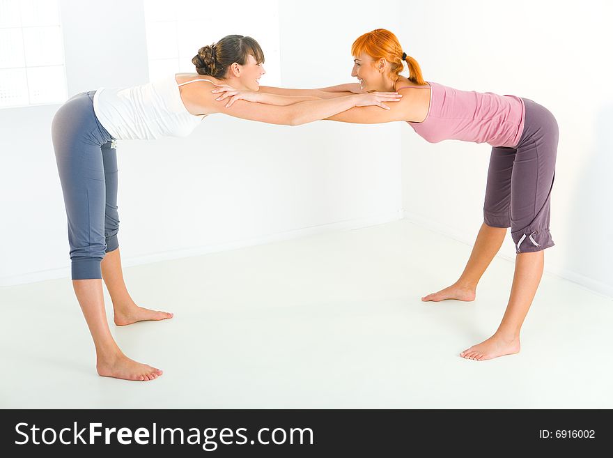 Two young women doing stretching exercises. Two young women doing stretching exercises.