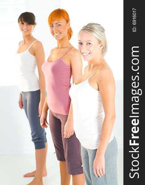 Three beautiful women dressed sportswear standing and looking at camera. Side view. Three beautiful women dressed sportswear standing and looking at camera. Side view.