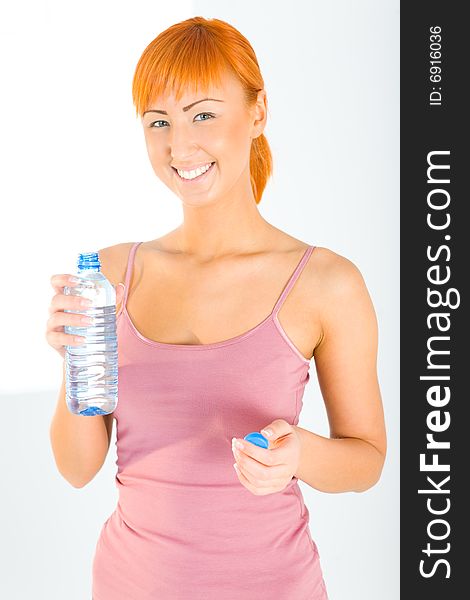 Young woman dressed sportswear holding water bottle. She's smiling and looking at camera. Front view. Young woman dressed sportswear holding water bottle. She's smiling and looking at camera. Front view.