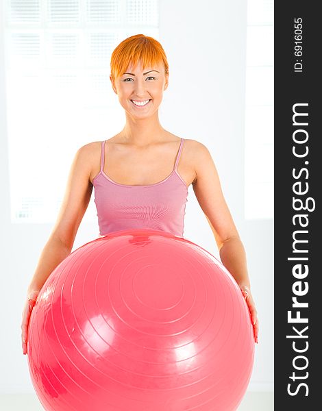 Young woman doing fitness exercise with big ball. She's looking at camera. Front view. Young woman doing fitness exercise with big ball. She's looking at camera. Front view.