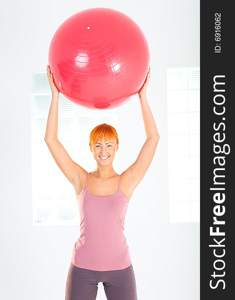 Young woman doing fitness exercise with big ball. She's looking at camera. Front view. Young woman doing fitness exercise with big ball. She's looking at camera. Front view.