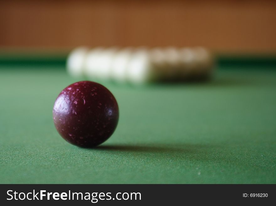 Close-up of beaten red billiard ball against blurred white balls on background. Close-up of beaten red billiard ball against blurred white balls on background