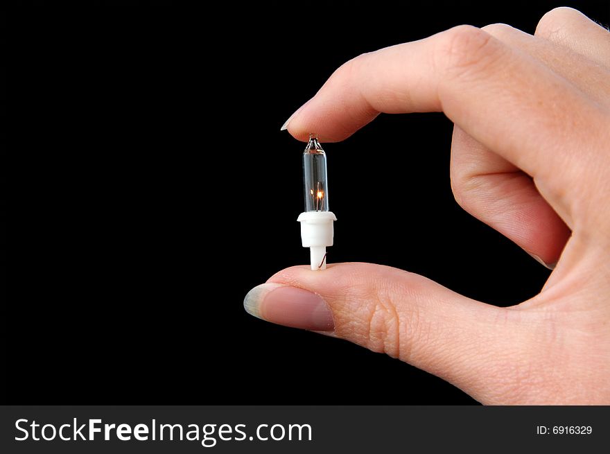 An Isolated to black image of a fairy (Christmas) light magically lit held between fingers. An Isolated to black image of a fairy (Christmas) light magically lit held between fingers