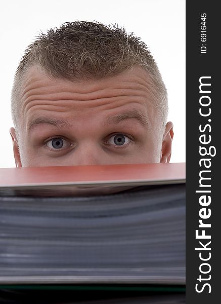 Man stashed  behind folders,with frown,against a white background.