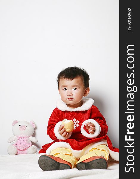 Santa baby in red dress with stuffed toy.