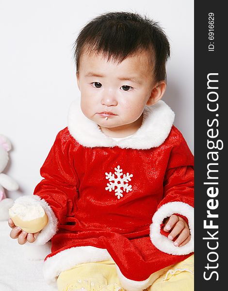 Santa baby in red dress eating a snack.