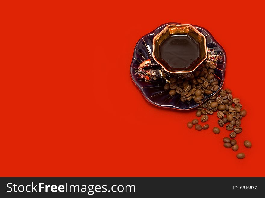 Coffee beans and a cup of coffee lying on the red background. Coffee beans and a cup of coffee lying on the red background