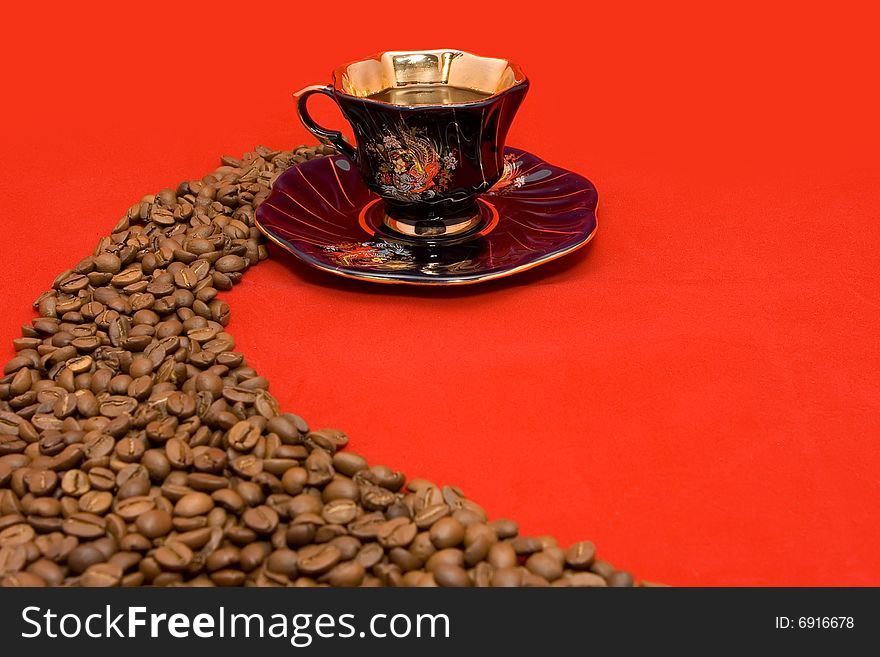 Coffee beans and a cup of coffee lying on the red background. Coffee beans and a cup of coffee lying on the red background
