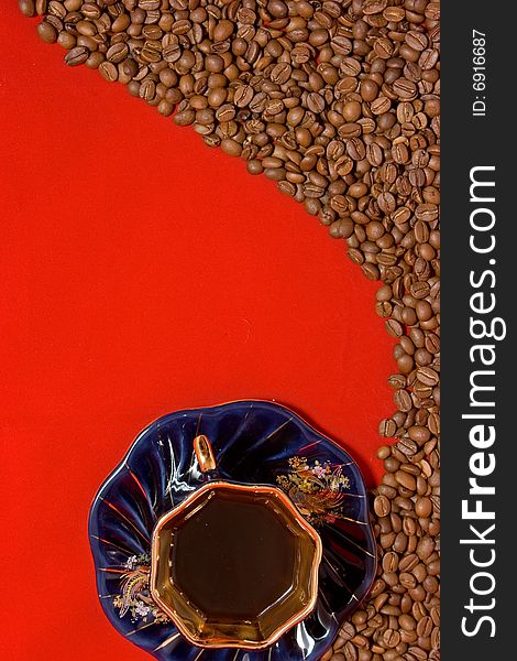 Coffee beans and a cup of coffee lying on the red background. Coffee beans and a cup of coffee lying on the red background