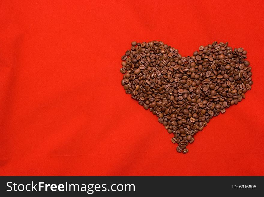 Heart made of coffee beans lying on the red background. Heart made of coffee beans lying on the red background