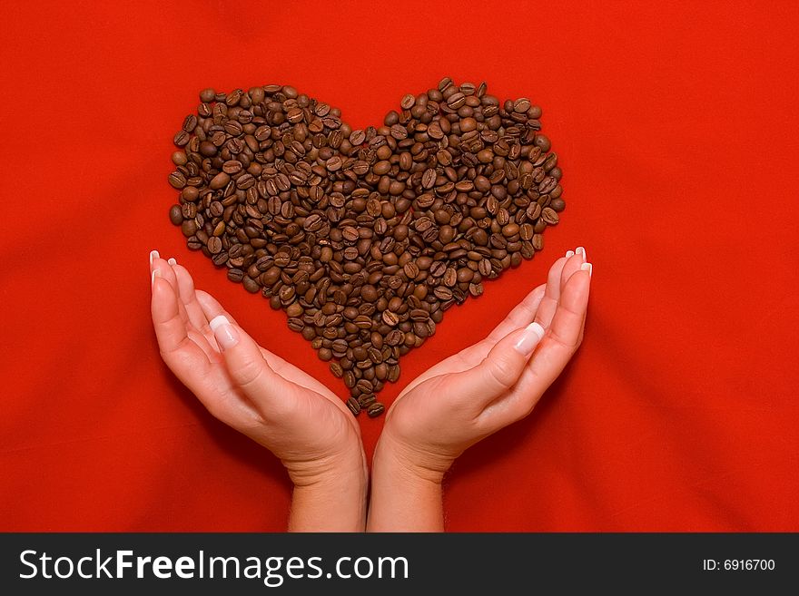 Heart made of coffee beans lying on the red background. Heart made of coffee beans lying on the red background