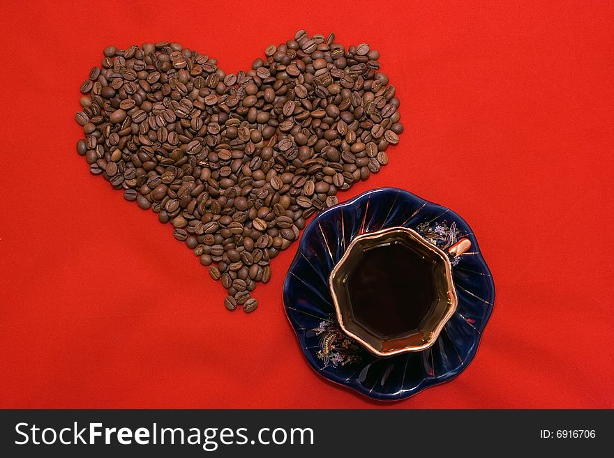 Heart made of coffee beans lying on the red background. Heart made of coffee beans lying on the red background