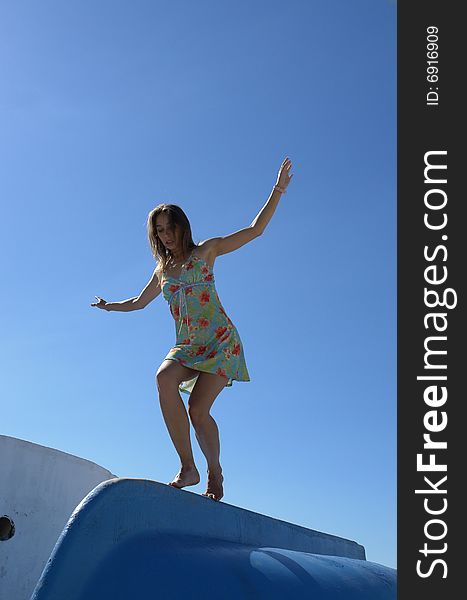 Girl dancing on the terned over boat on the blue sky background. Girl dancing on the terned over boat on the blue sky background