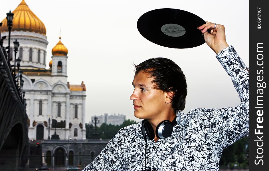 DJ Roman Kravtsov with his headphones holding vinyl over the head. DJ Roman Kravtsov with his headphones holding vinyl over the head