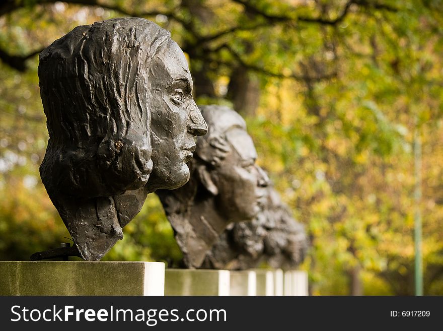 Sculptures of polish historical scientists in a park in autumn scenery.