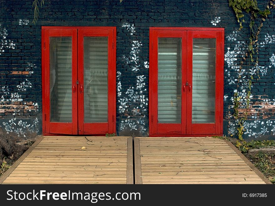 In the picture, there are two red doors with printed wall. In the picture, there are two red doors with printed wall.