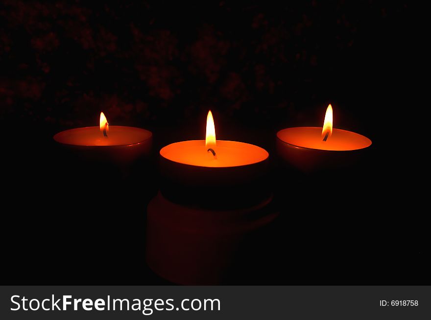 Three candles against a dark background