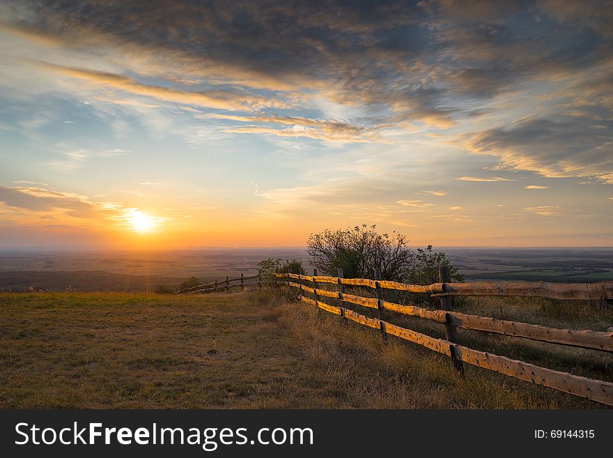 Meadow with wooden fence in the sunset