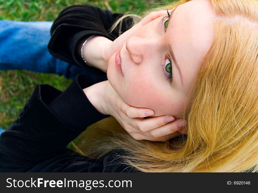 Portrait of the beautiful blonde sitting on a grass in park. Portrait of the beautiful blonde sitting on a grass in park