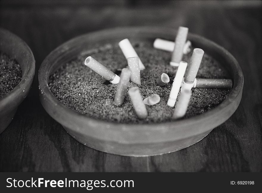 Black and white image of several cigarettes in an ashtray.