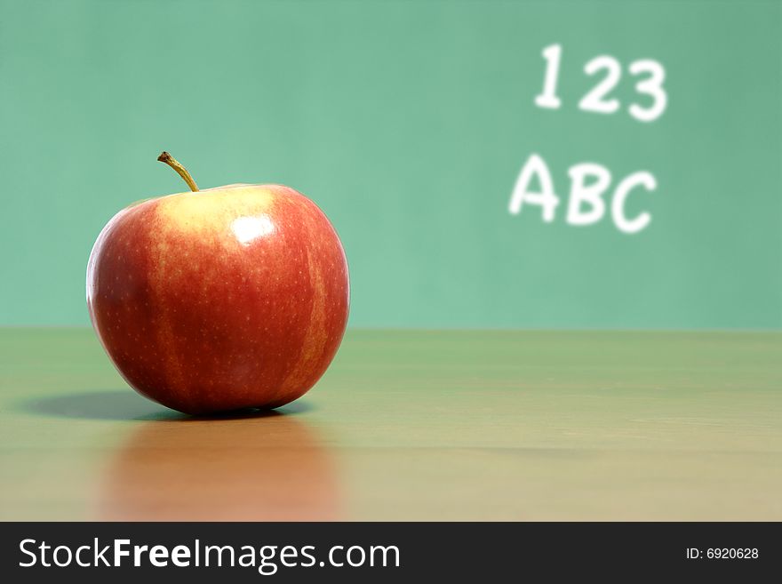 An apple on a desk in a classroom with abc 123