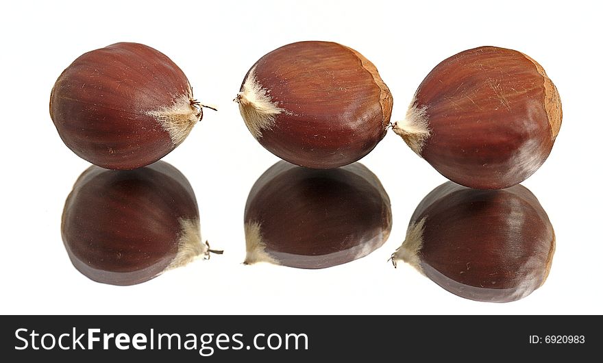 Three chestnuts on a reflective surface