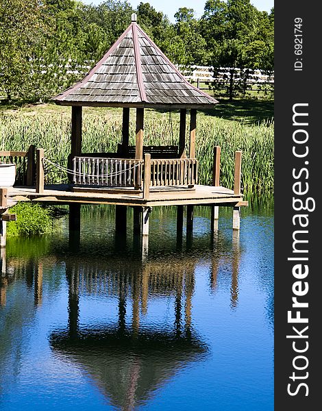 Gazebo with wooden shingles at pond with blue reflection. Gazebo with wooden shingles at pond with blue reflection