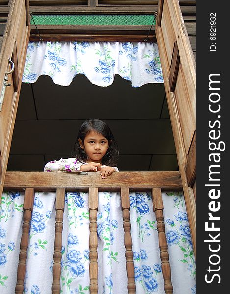 A Malaysian girl wearing malay  traditional clothe standing by window in a traditional malay house.