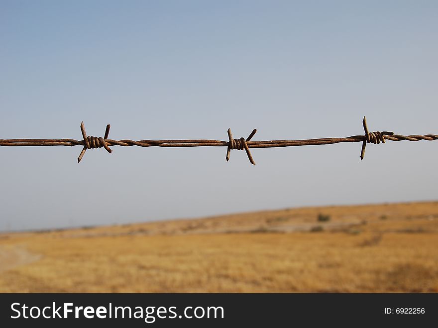 Fragment of old barbed wire on boundless open space background