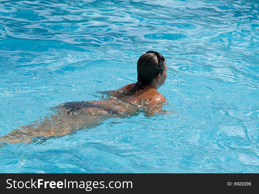 Young woman swims in a swimming pool. Young woman swims in a swimming pool