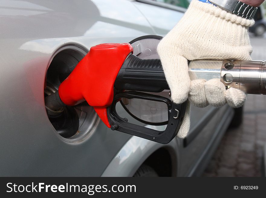 Bright red gas pump inserted into an automobile gasoline tank. Bright red gas pump inserted into an automobile gasoline tank