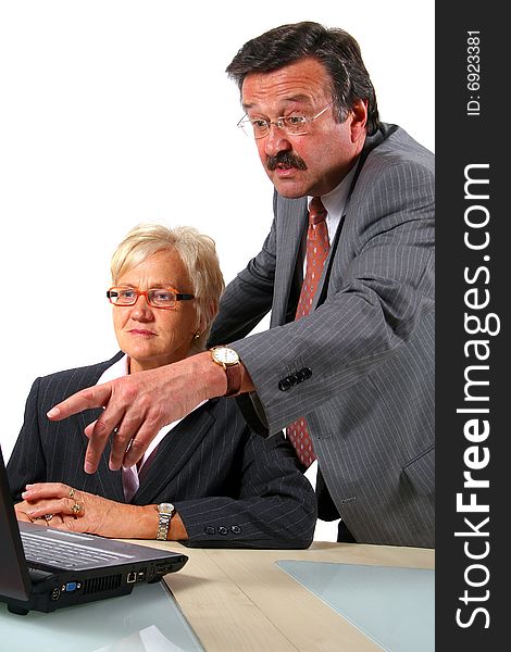 A business woman and a man in front of a laptop on a desk. The man explains something to the woman. Isolated over white. A business woman and a man in front of a laptop on a desk. The man explains something to the woman. Isolated over white.
