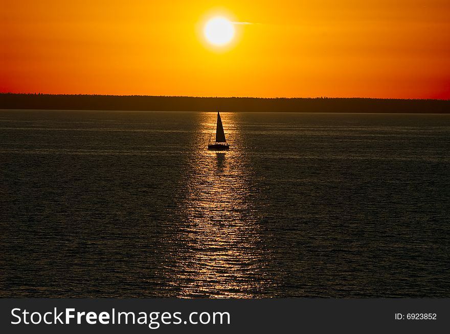 Sailing boat passing sunset reflecting are  from sea. Sailing boat passing sunset reflecting are  from sea