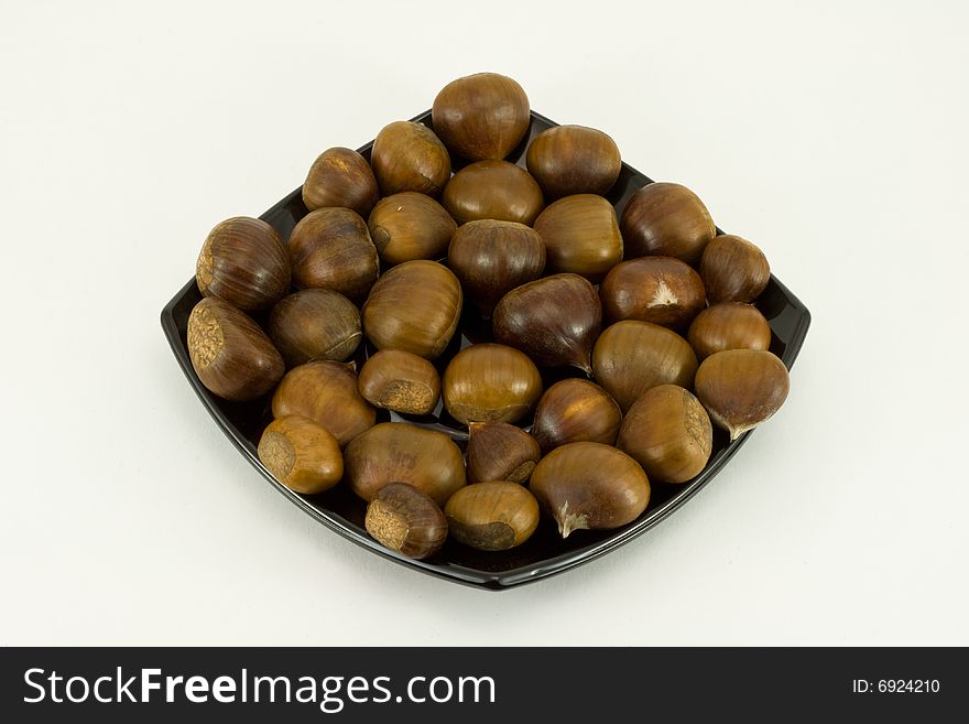 Chestnuts on dark plate isolated on white background