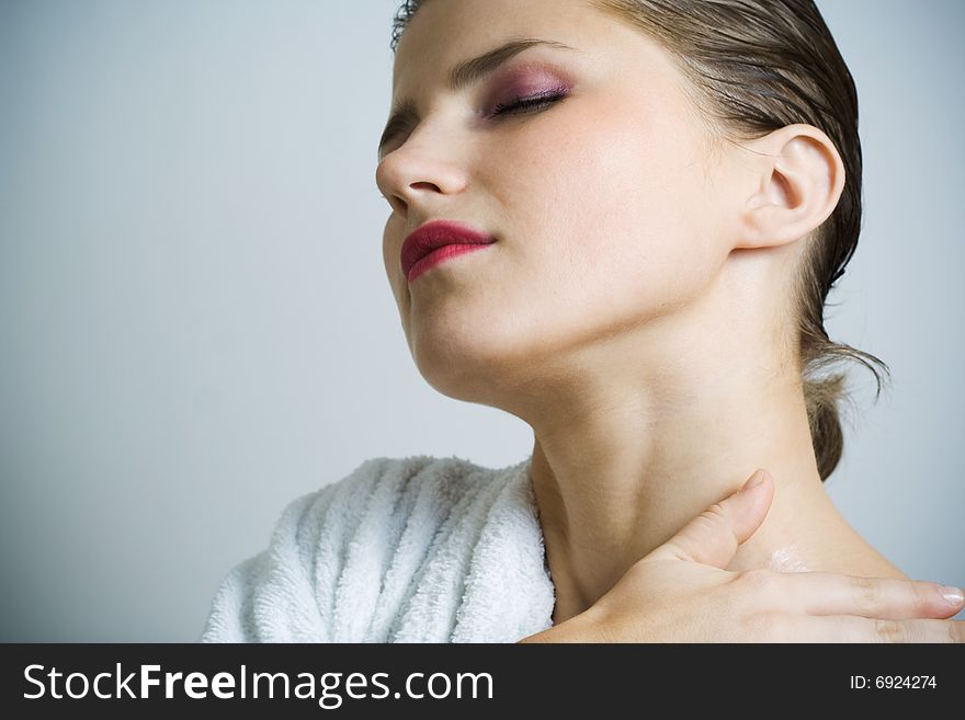 Beautiful woman in bathrobe massaging her skin. Beautiful woman in bathrobe massaging her skin.