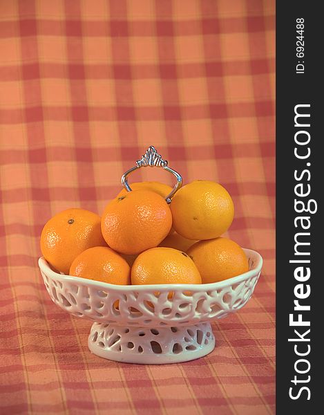 Luxe white Bowl filled with mandarin fruit on an orange checkered background. Luxe white Bowl filled with mandarin fruit on an orange checkered background